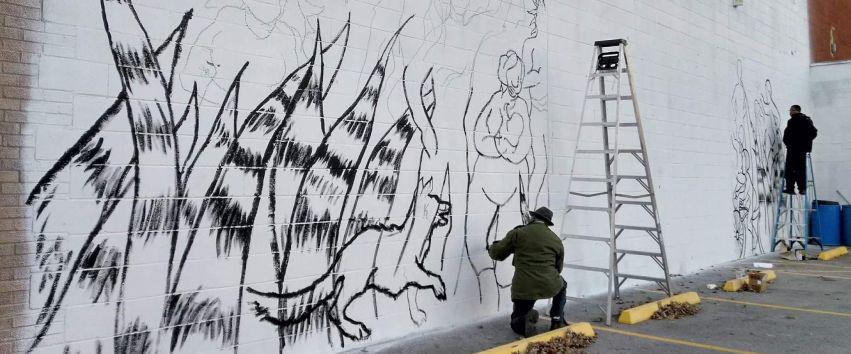 Preston Jackson works on a mural to enliven the space outside of Proctor Center on the Southside of Peoria.