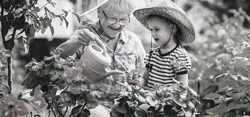 older woman and child watering a garden