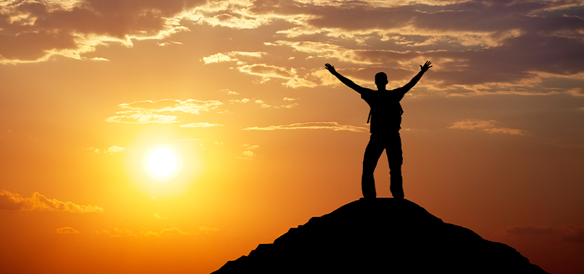 Person on a mountain silhouetted by a sunset