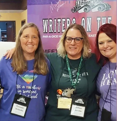 Women standing in front of an event poster.